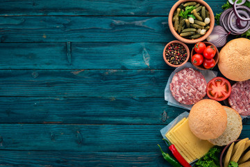 Preparation of burger. Meat, tomatoes, onions. On a blue wooden background. Top view. Free copy space.