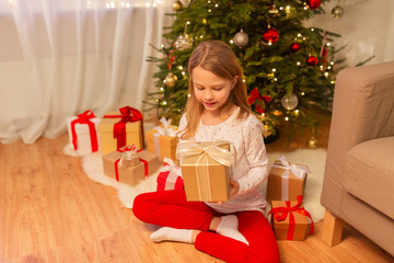 christmas, holidays and childhood concept - smiling girl with gift box at home