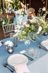 Festive table decorated with flowers and candles on a silver candlestick on blue tablecloth