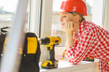 Woman using drill to fix or installing windows