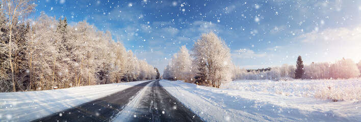 winter road, covered with snow on sunny day. Black icy asphalt