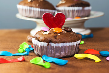 red wooden heart on birthday party chocolate arabic homemade cupcake, madeleine with colorful ballons and smarties