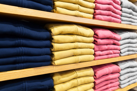 shopping, sale and retail concept - close up of shelves with clothes at clothing store