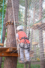Portrait of cute little boy and girl walk on a rope bridge in an adventure rope park.