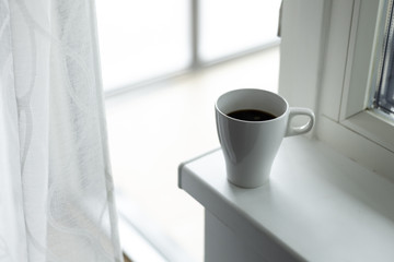 A cup of coffee on the windowsill. Big window. Scandinavian style