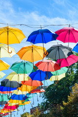 Obraz na płótnie Canvas Different colorful umbrellas hanging over the street against sky