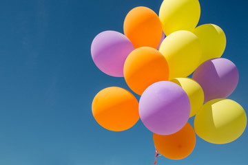 birthday, celebration and party decoration concept - close up of colorful balloons inflated with helium in blue sky