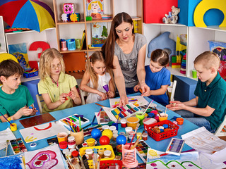 Fototapeta premium Plasticine modeling clay in children class. Clay projects with teacher teaches kids together play dough and mold in kindergarten or preschool.