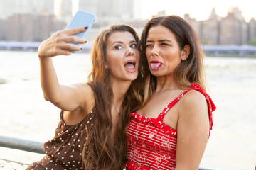 Two young women in New York taking a selfie photo with their smartphone