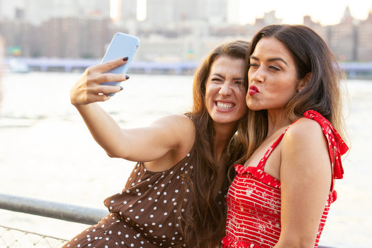 Two young women in New York taking a selfie photo with their smartphone