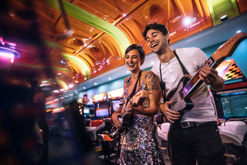 Smiling man and woman playing the guitar game at a gaming arcade