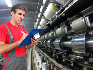 Quality Control in Textile Industry / Quality control inspector using clipboard and writing in...