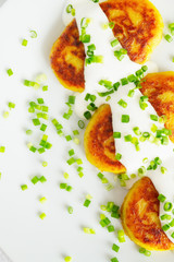 fried potato cutlets with sour cream decorated with green onion