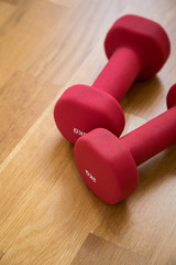Zwei rote Kurzhanteln auf Holz für Fitness Training