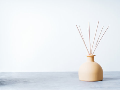 aroma reed diffuser home fragrance with rattan sticks on a light background with palm leaves and shadows.