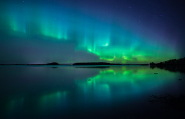 Northern lights dancing over calm lake in Farnebofjarden national park in Sweden