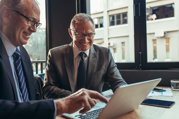 Business partners working together on laptop at cafe