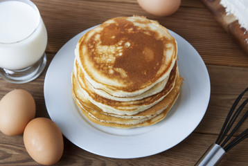 Cooking pancake on wooden background top view ingredients for making pancakes: milk, eggs, flour.