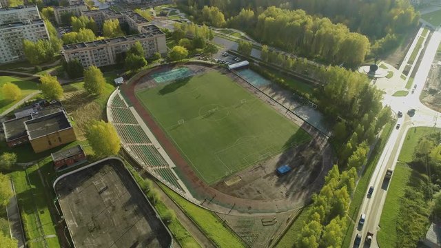 Flying over the stadium in the city summer sunny morning with green park