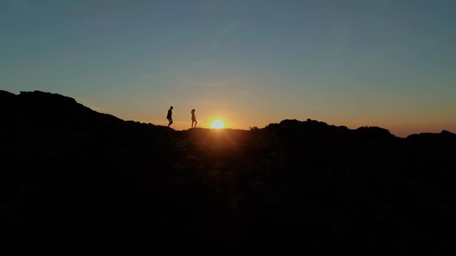 Young couple silhouette walk in beautiful sunset on mountain landscape peak or top. Concept of hike and camp, nature outdoor exploration to find new travel destination for blogger content post