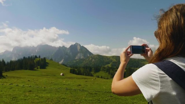 Salzburgerland Austria, young woman taking picture of mountain landscape