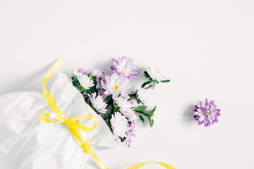 Flowers composition. Pattern made of purple flowers in a white paper bag on white background. Flat lay, top view, copy space 