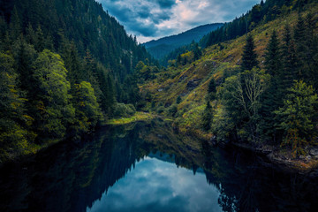 A beautiful lake located deep in the mountains surrounded by a forest at the beggining of autumn on...