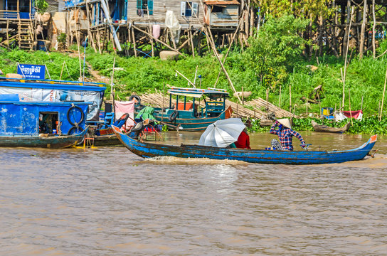 Women rowing a long-tail boat along the banks of Tonle Sap Lake in Cambodia