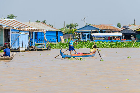  Floating village on the Tonle Sap Lake in Cambodia and kids rowing home with their wooden boat
