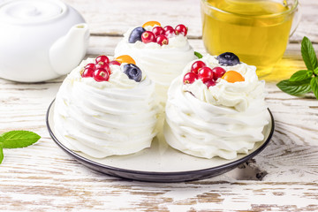 Delicious mini Pavlova meringue cake decorated with fresh red currant and blueberry