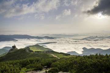 Small silhouette of tourist with raised arms on rocky formation on mountain valley filled with...