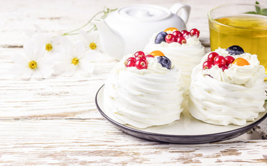 Delicious mini Pavlova meringue cake decorated with fresh red currant and blueberry