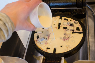 An adult prepares to make waffles at the waffle station at hotel. Many hotels give guests a free continental breakfast during their stay