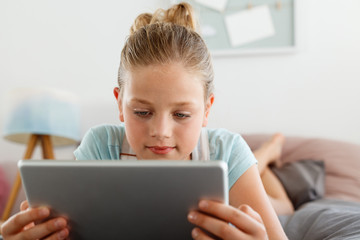 Cute girl using digital tablet in her bedroom