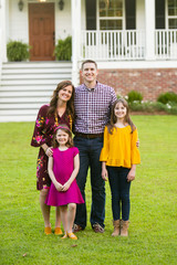 Fototapeta premium Family of Four with Daughters Outside their New Construction Farmhouse Home with Curb Appeal