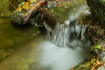 Naklejka na ściany i meble Nature waterfall at mountain river cascade. Colorful green mossy rocks, waterfall and cascade. Nature background.