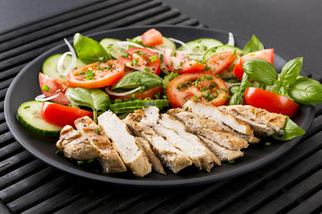 Vegetable salad and grilled chicken on a black background. Healthy food. Diet.