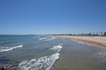 landscape beach in Castellon, named Gurugu, in Valencia, Spain, Europe. Blue clear sky, Mediterranean Sea and Grao harbor in the horizon