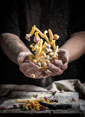 close hand make pasta and throw on a black background before cooking the dish