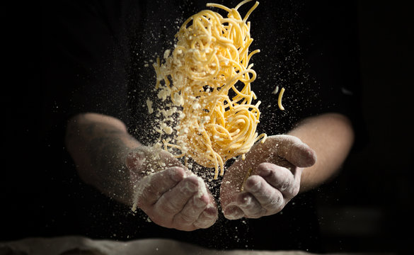 close hand make pasta toss on a black background before cooking the dish