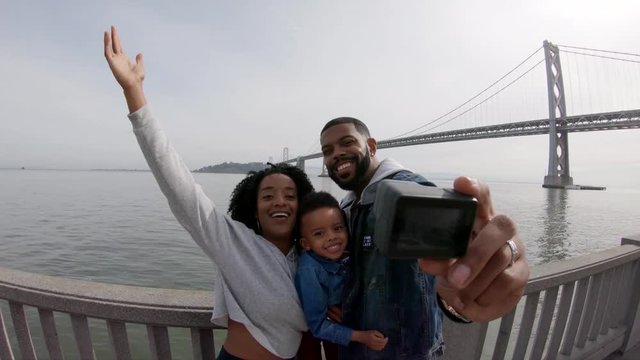 Panning shot, happy family poses by Oakland Bay Bridge