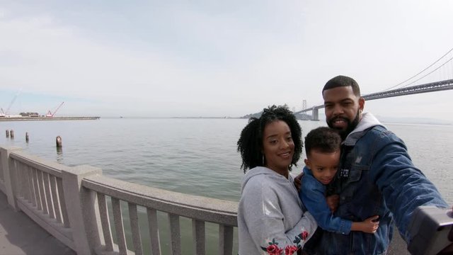 Family poses by Oakland Bay Bridge, California