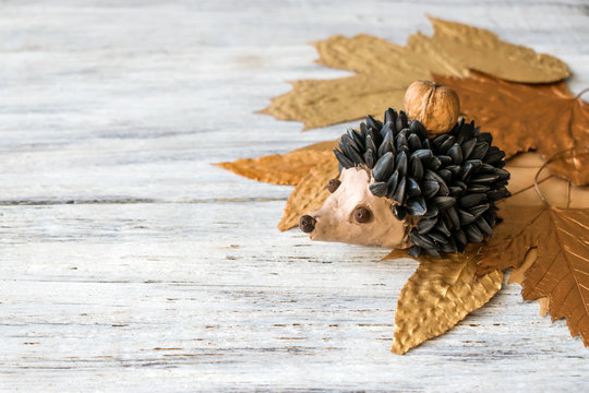 Autumn crafts. Children's fall crafts and creativity, Hedgehog made from modeling clay, sunflower seeds and nuts, on dry yellow leaves. Ideas for children's art