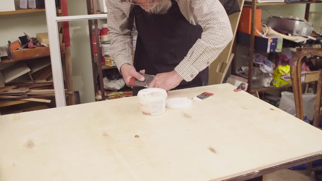 Crane shot. High angle view. Senior carpenter spackling wooden board