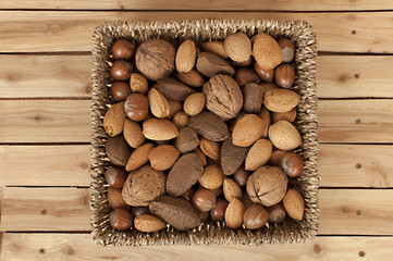 different kind of nuts in straw basket on wooden table