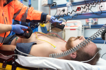 Medical urgency in the ambulance. Emergency doctor using defibrillator - obrazy, fototapety, plakaty