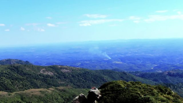 Wide shot panoramic view of open landscape from a mountain side. Smoke seen in the distance. fog seen at end of the shot.