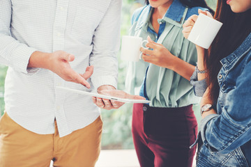 Casual businessman hand showing presentation on tablet to team for new startup project. Business meeting. Young coworker making relax business discussion in modern office. Teamwork people concept