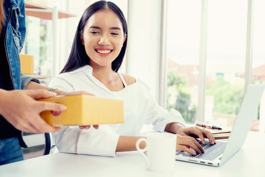 Business owner concept. Young two asian woman smiling happy using laptop working and checking customer product packaging for online order in modern home office