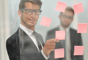 serious employee reads a sticker-note on the office Board.